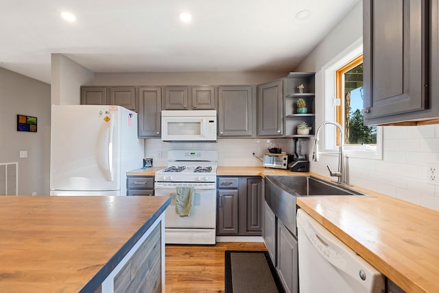 kitchen featuring wood counters, light wood-type flooring, gray cabinetry, white appliances, and sink