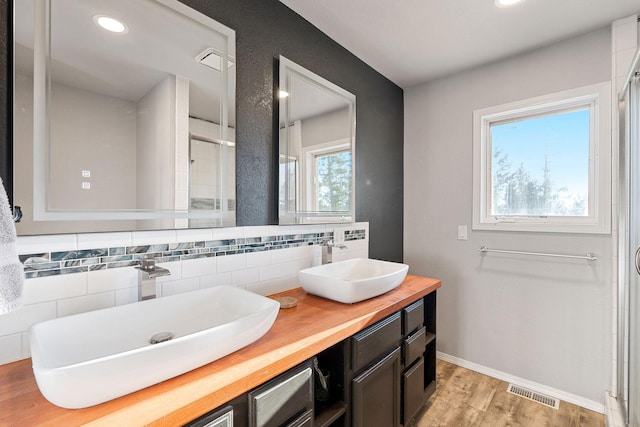 128 Ledgewood Dr, Bigfork, MT 59911 - bathroom with tasteful backsplash, double vanity, wood finished floors, recessed lighting, and a shower with shower door