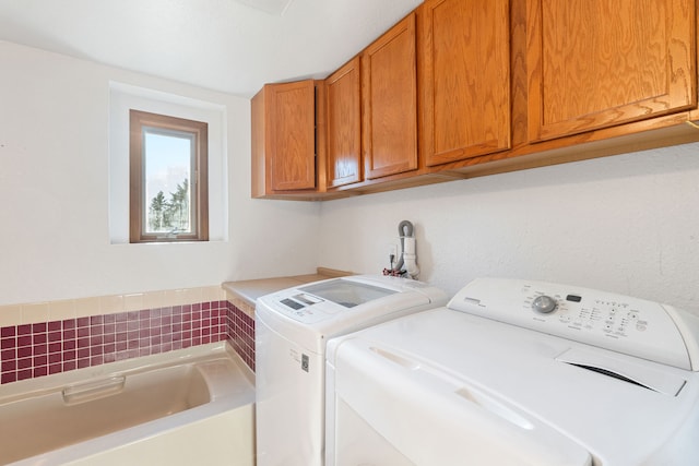 washroom with washing machine and clothes dryer and cabinets