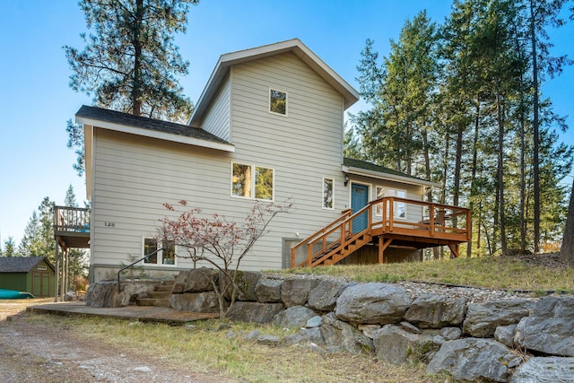 128 Ledgewood Dr, Bigfork, MT 59911 - back of property with a wooden deck, a storage shed, and stairway