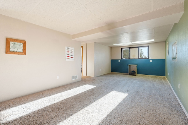 spare room featuring carpet flooring and a drop ceiling