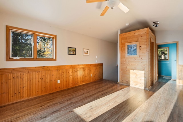 spare room featuring hardwood / wood-style flooring, vaulted ceiling, ceiling fan, and wooden walls