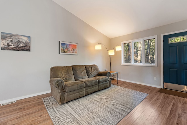 living room featuring wood-type flooring and vaulted ceiling