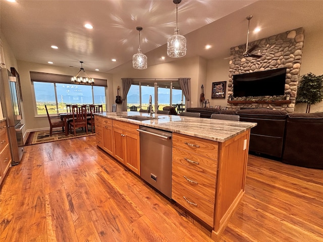 kitchen featuring stainless steel appliances, sink, decorative light fixtures, and light hardwood / wood-style flooring