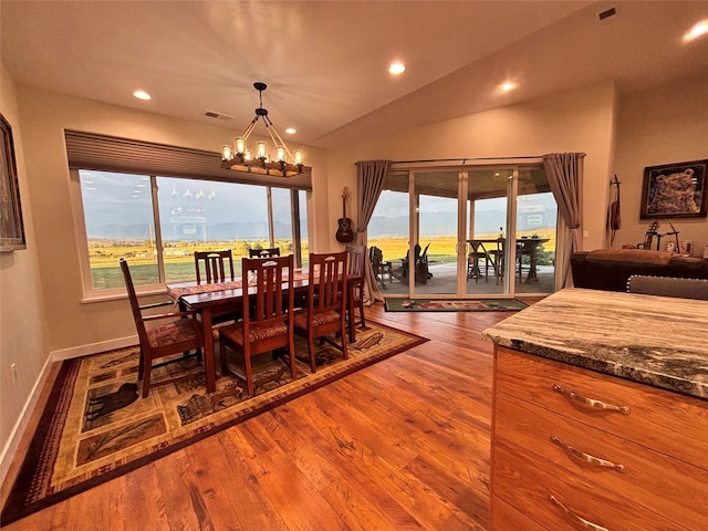 dining room featuring wood-type flooring, an inviting chandelier, and vaulted ceiling