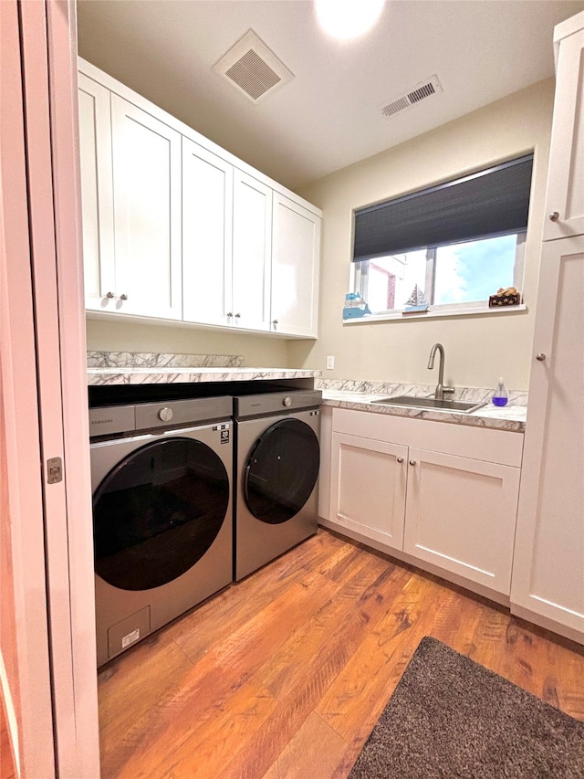 washroom featuring cabinets, separate washer and dryer, light hardwood / wood-style floors, and sink