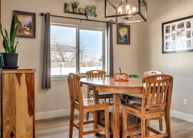 dining area with light wood-type flooring and an inviting chandelier