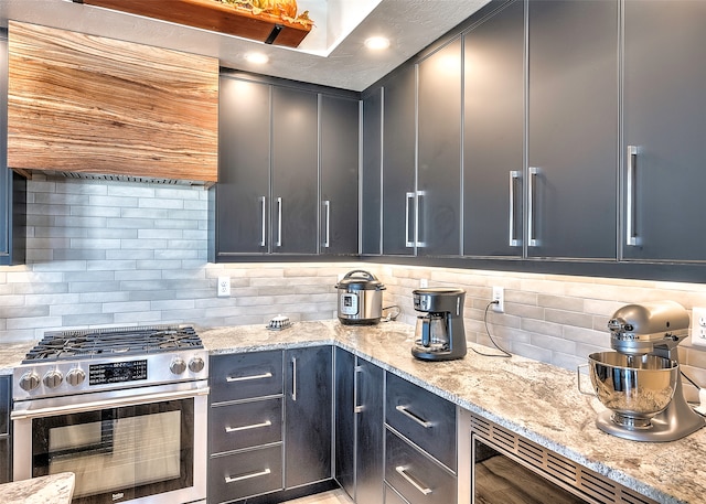 kitchen with wine cooler, light stone countertops, decorative backsplash, and high end range