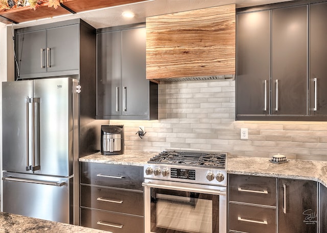 kitchen featuring high end appliances, tasteful backsplash, and light stone counters