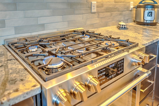 room details featuring stone counters, tasteful backsplash, and gas stove