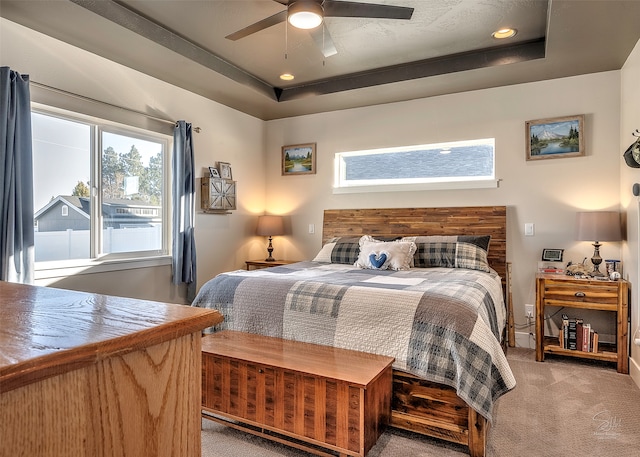 bedroom with carpet floors, ceiling fan, and a tray ceiling