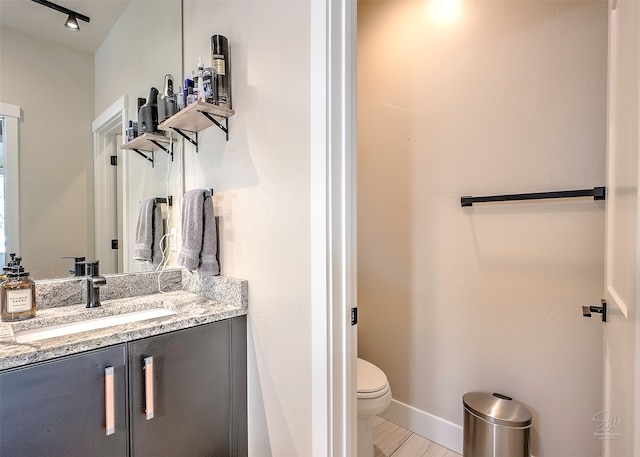 bathroom with toilet, vanity, and wood-type flooring