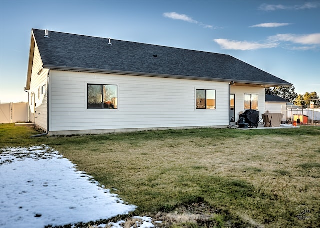 snow covered house featuring a patio and a yard