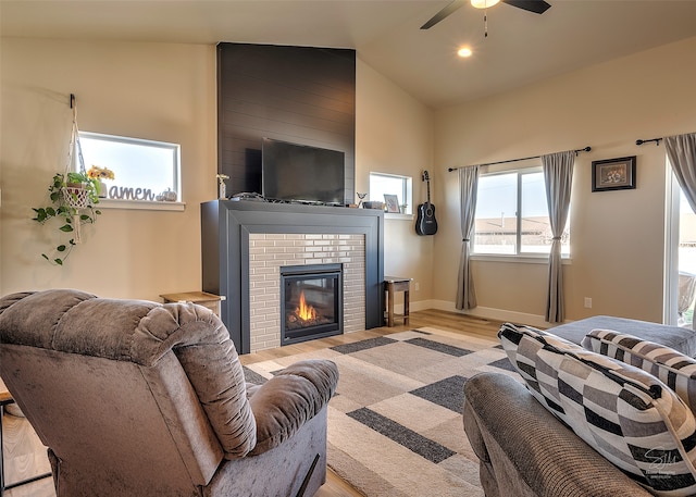 living room featuring a fireplace, vaulted ceiling, ceiling fan, and light hardwood / wood-style flooring