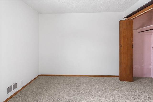 unfurnished room featuring baseboards, a textured ceiling, visible vents, and carpet flooring