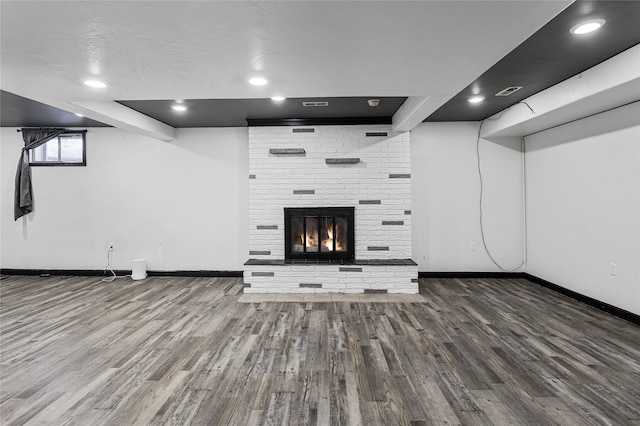 unfurnished living room featuring a brick fireplace, hardwood / wood-style flooring, and a textured ceiling