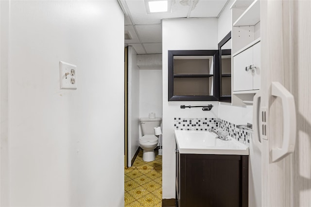 bathroom with toilet, a paneled ceiling, vanity, and tile patterned floors