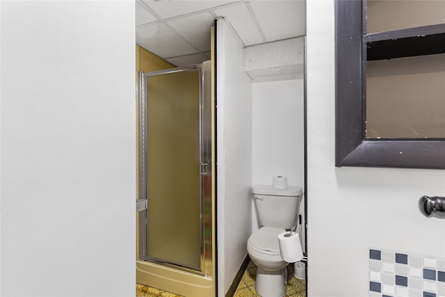 bathroom featuring a drop ceiling, a shower stall, and toilet