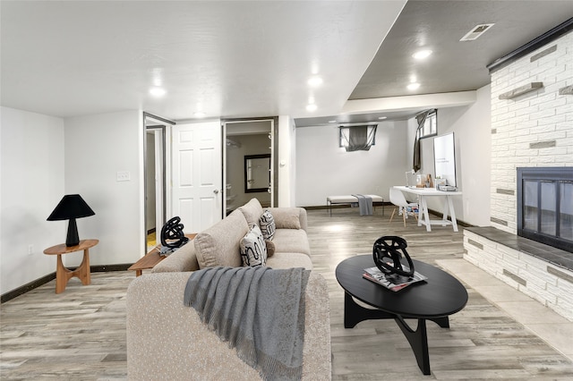 living room with recessed lighting, a fireplace, visible vents, baseboards, and light wood-style floors