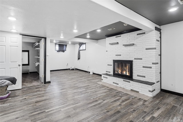 unfurnished living room with recessed lighting, a fireplace, wood finished floors, and baseboards