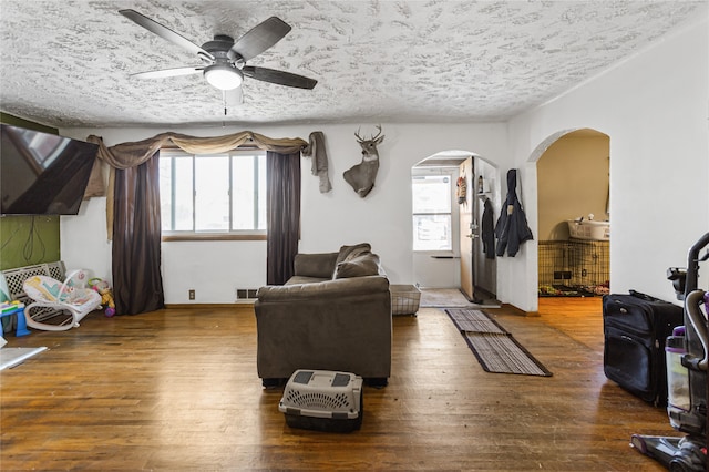 living room with hardwood / wood-style floors, a textured ceiling, and ceiling fan