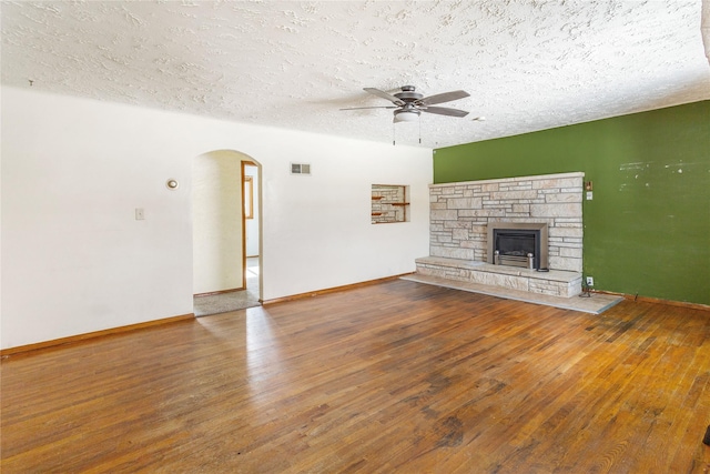 unfurnished living room featuring visible vents, arched walkways, a ceiling fan, hardwood / wood-style flooring, and a textured ceiling