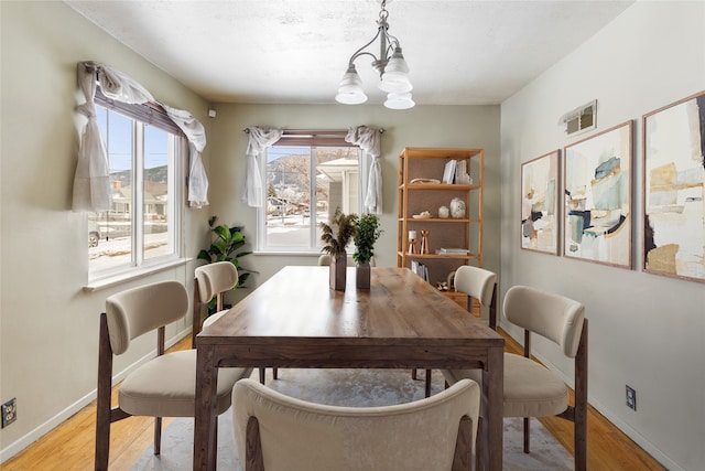 dining area with a chandelier, baseboards, and light wood-style floors