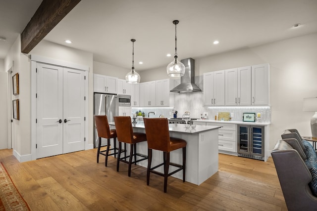 kitchen featuring white cabinetry, light hardwood / wood-style flooring, wall chimney range hood, and a kitchen island