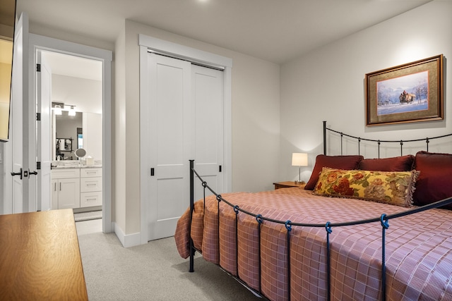 bedroom featuring a closet, light colored carpet, and ensuite bathroom