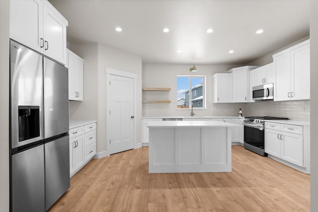 kitchen with stainless steel appliances, light countertops, open shelves, and white cabinetry