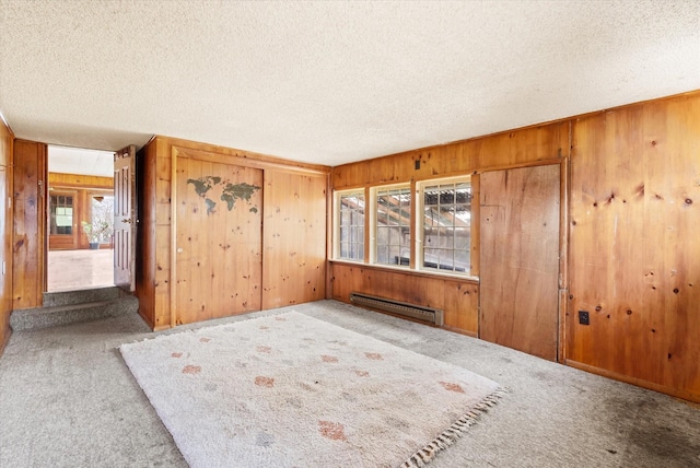 1312 2nd Ave E, Kalispell, MT 59901 - spare room featuring baseboard heating, carpet floors, wood walls, and a textured ceiling
