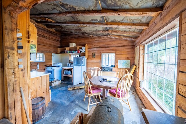 dining room with lofted ceiling with beams and wooden walls