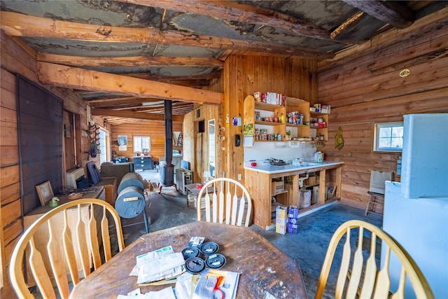 dining area with a workshop area, beamed ceiling, and wooden walls