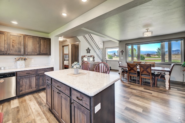 kitchen featuring dishwasher, a kitchen island, dark brown cabinets, and light hardwood / wood-style flooring