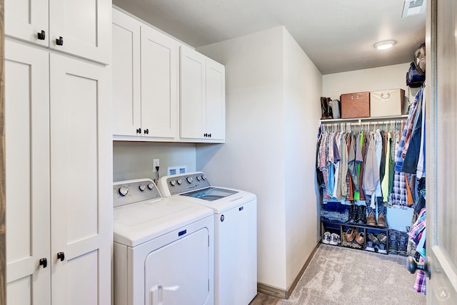 washroom featuring cabinets, washing machine and dryer, and light carpet