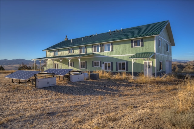 rear view of property featuring a mountain view, solar panels, and cooling unit