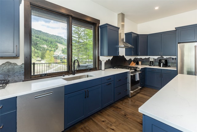 3868 Gelande St Unit 4, Whitefish, MT 59937 - kitchen with blue cabinetry, wall chimney range hood, a sink, and stainless steel appliances