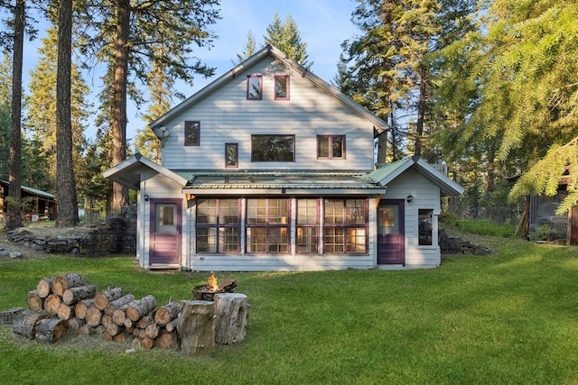 rear view of property featuring a sunroom and a yard