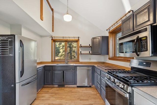 kitchen featuring sink, hanging light fixtures, stainless steel appliances, gray cabinets, and light wood-type flooring