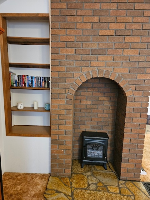 interior details featuring built in features, carpet flooring, and a wood stove