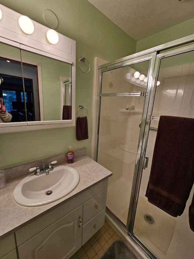 bathroom featuring vanity, a textured ceiling, tile patterned flooring, and a shower with shower door