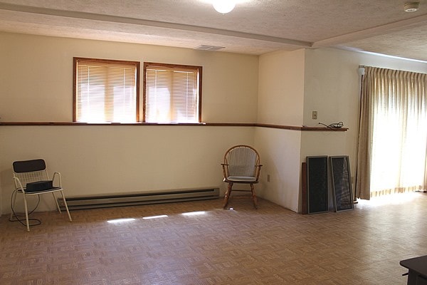 spare room with a textured ceiling, a healthy amount of sunlight, and a baseboard radiator