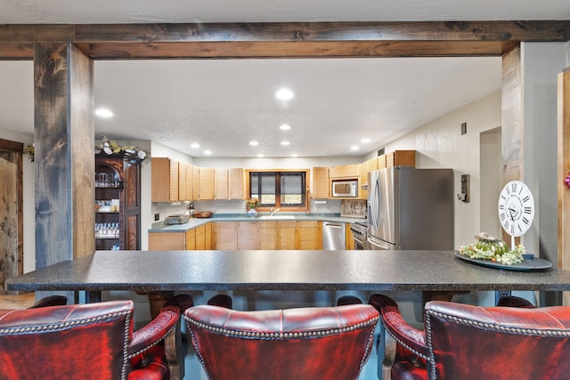 16485 Folsom Rd, Florence, MT 59833 - kitchen featuring appliances with stainless steel finishes, a sink, a kitchen bar, light brown cabinetry, and recessed lighting