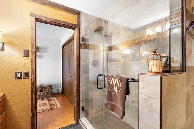 16485 Folsom Rd, Florence, MT 59833 - bathroom with baseboard heating, a shower stall, wood finished floors, and a textured wall