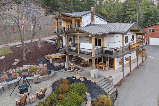 16485 Folsom Rd, Florence, MT 59833 - rear view of property featuring a standing seam roof, metal roof, a balcony, a patio, and a view of trees