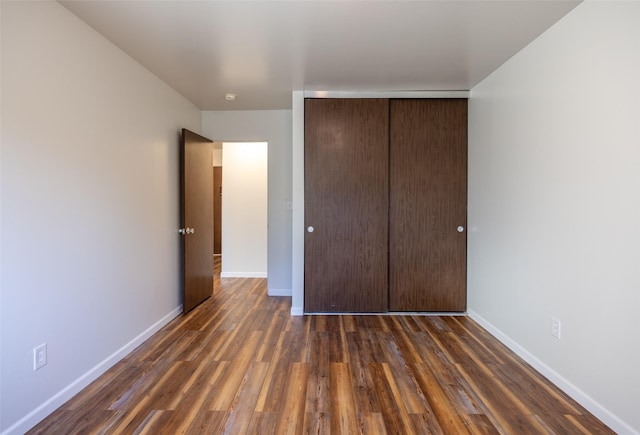 unfurnished bedroom with a closet and dark hardwood / wood-style flooring