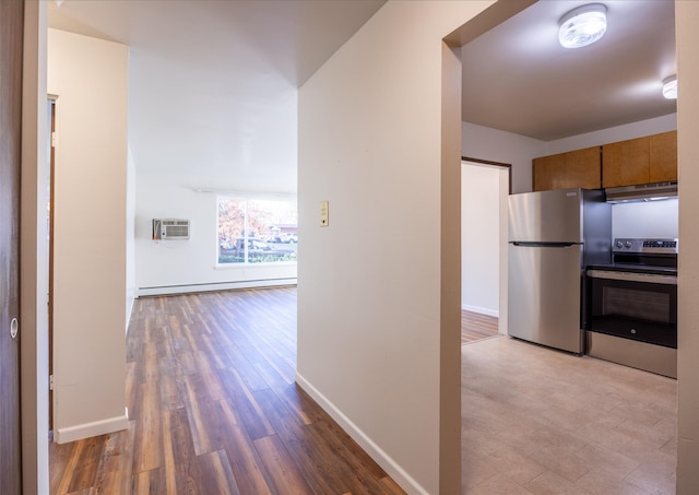 hall with baseboard heating, a wall mounted AC, and light hardwood / wood-style floors