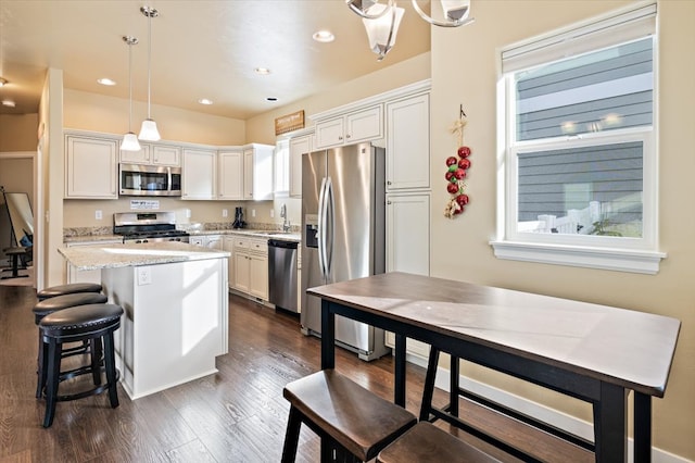 kitchen with pendant lighting, white cabinetry, stainless steel appliances, and a kitchen island