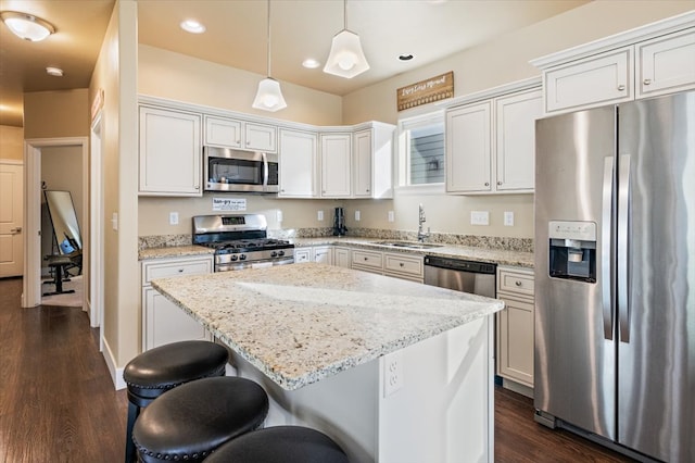 kitchen featuring sink, white cabinetry, decorative light fixtures, a center island, and appliances with stainless steel finishes