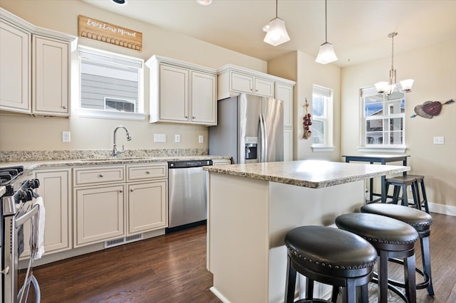 kitchen with pendant lighting, stainless steel appliances, a center island, and a breakfast bar